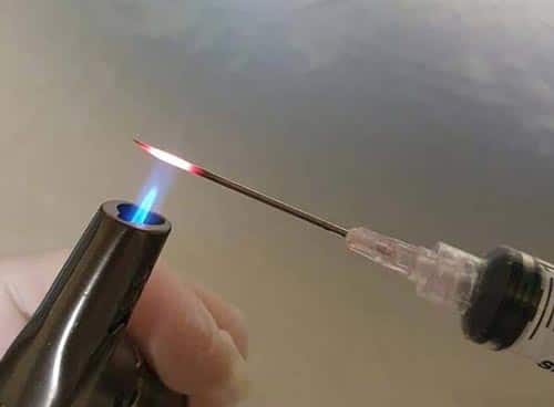 Flame sterilising a syringe needle